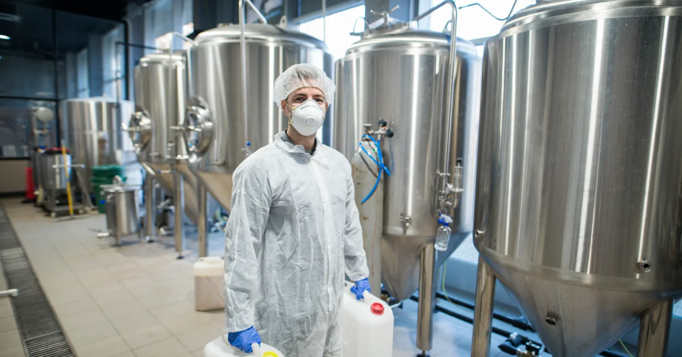 industrial-worker-technologist-white-protective-suit-with-hairnet-mask-holding-plastic-cans-with-chemicals-food-factory-production-line_11zon کارخانه تولید پنیر پیتزا